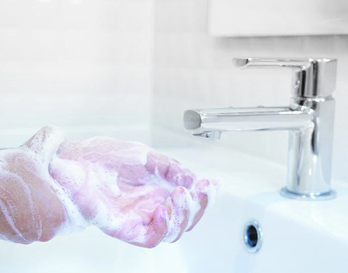 Soapy hands being washed in a sink
