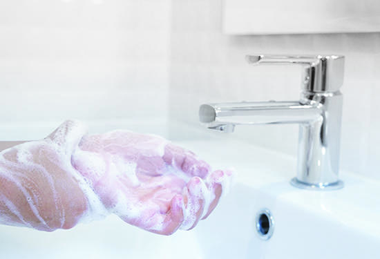 Soapy hands being washed in a sink